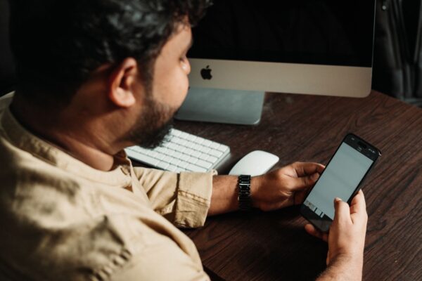 A person using a smartphone in the morning next to someone working at a desktop computer during the day, illustrating shifting device usage throughout the day.